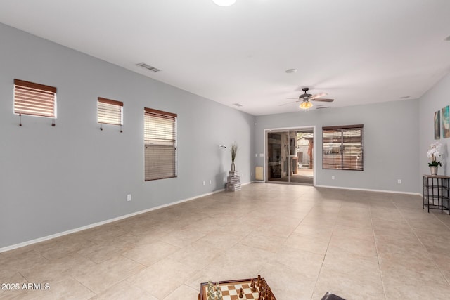 unfurnished living room featuring visible vents, plenty of natural light, baseboards, and a ceiling fan