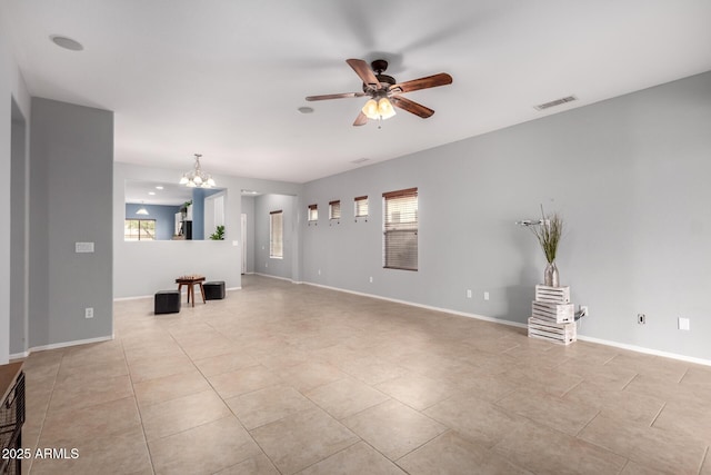 unfurnished living room with a wealth of natural light, visible vents, baseboards, and ceiling fan with notable chandelier