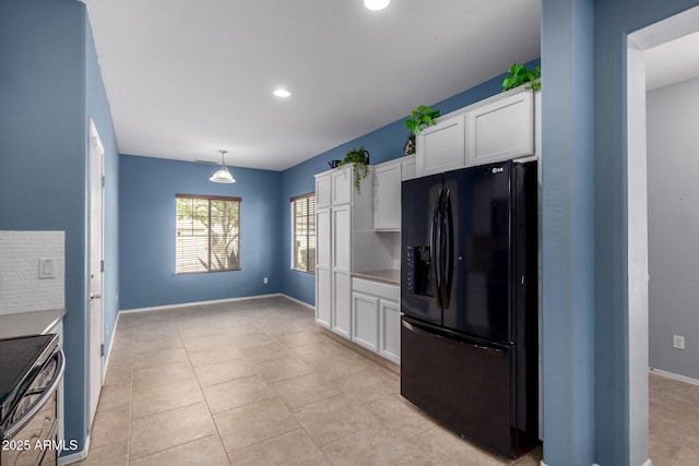 kitchen featuring stainless steel electric range oven, baseboards, black refrigerator with ice dispenser, and white cabinetry