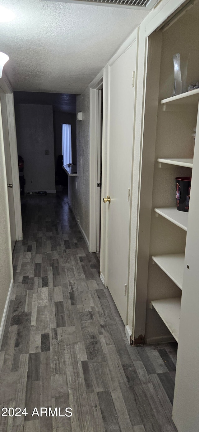 corridor featuring dark hardwood / wood-style flooring and a textured ceiling