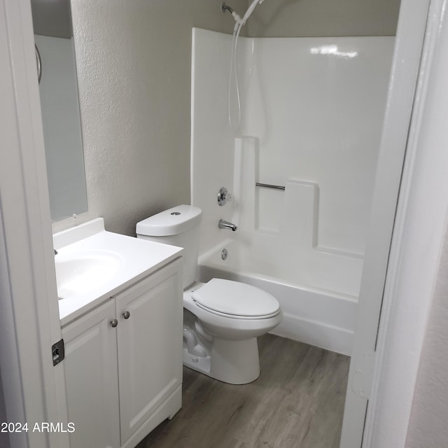 full bathroom with wood-type flooring, toilet,  shower combination, and vanity