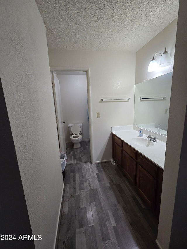 bathroom featuring hardwood / wood-style floors, vanity, a textured ceiling, and toilet