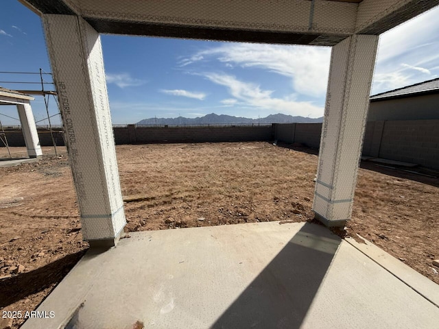 view of yard featuring a patio area, a fenced backyard, and a mountain view