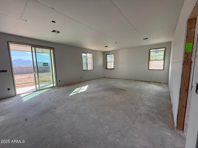 unfurnished room featuring unfinished concrete floors and a mountain view