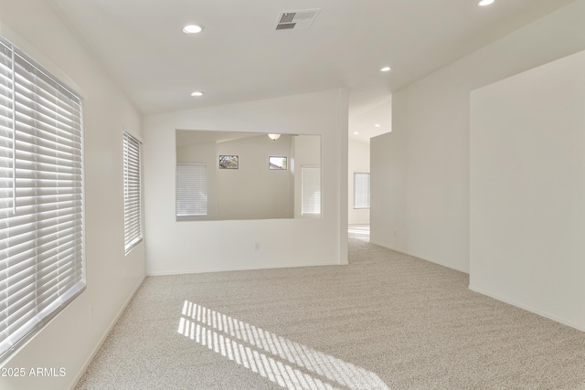 empty room with a healthy amount of sunlight, vaulted ceiling, and light colored carpet