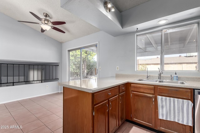 kitchen featuring sink, vaulted ceiling, light tile patterned floors, stainless steel dishwasher, and kitchen peninsula