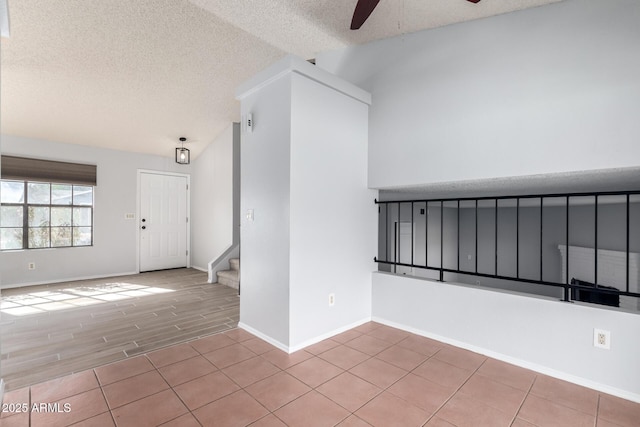 unfurnished room featuring ceiling fan, vaulted ceiling, a textured ceiling, and light wood-type flooring