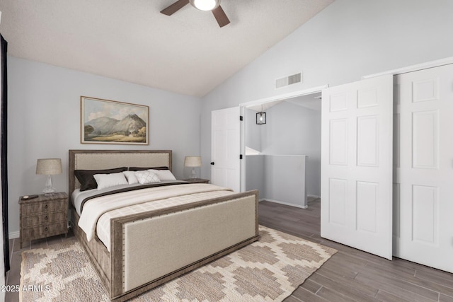 bedroom with ceiling fan, vaulted ceiling, a barn door, and wood-type flooring