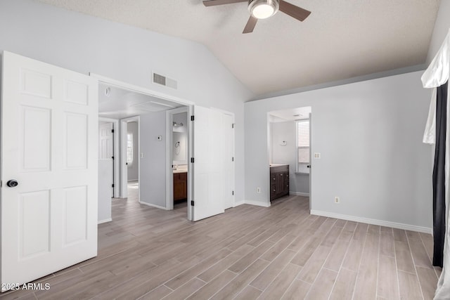 unfurnished bedroom with ceiling fan, ensuite bath, vaulted ceiling, and light wood-type flooring