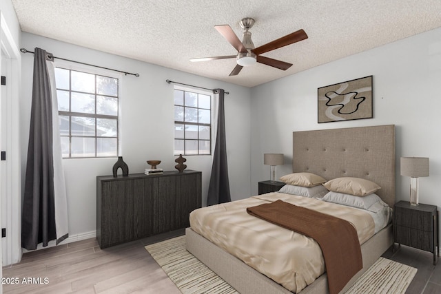 bedroom with ceiling fan, wood-type flooring, and a textured ceiling