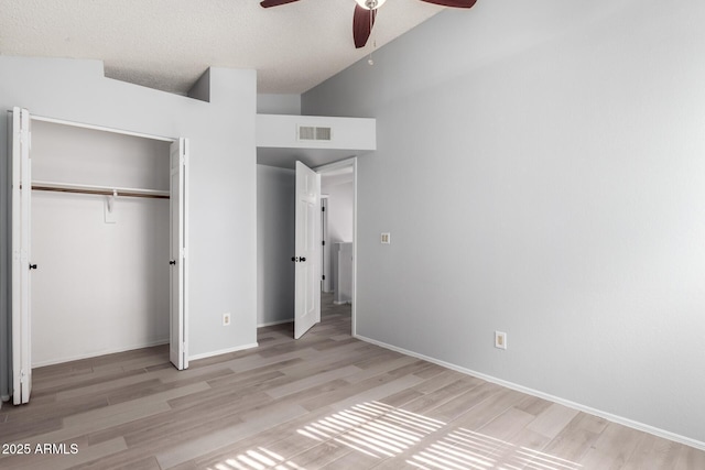 unfurnished bedroom with vaulted ceiling, a textured ceiling, light wood-type flooring, a closet, and ceiling fan