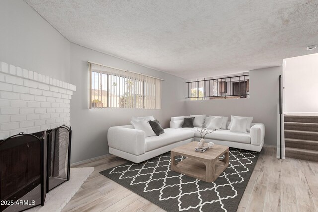 living room featuring a fireplace, wood-type flooring, and a textured ceiling