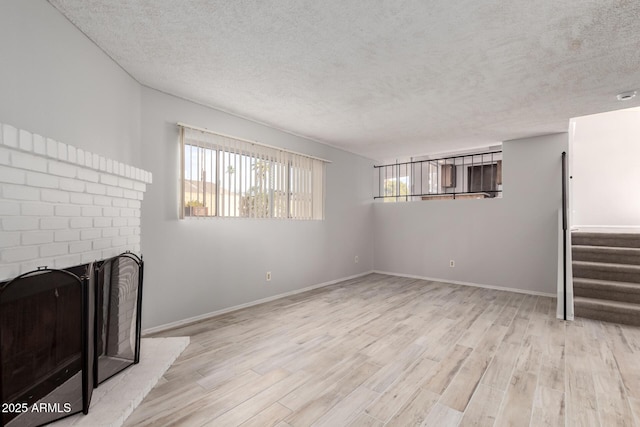 unfurnished living room featuring a fireplace, plenty of natural light, and light wood-type flooring