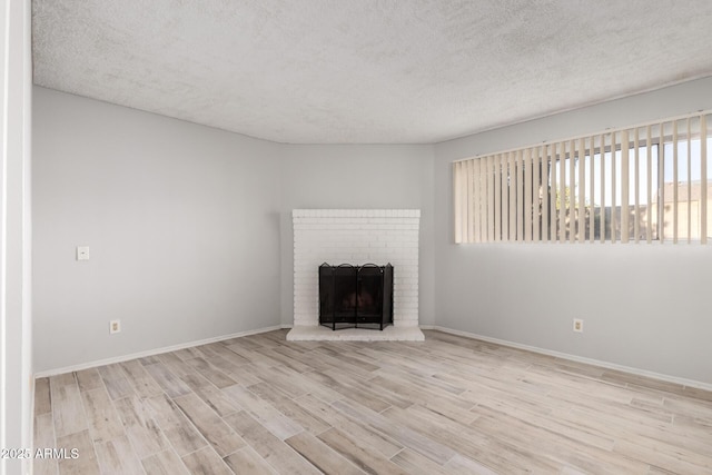 unfurnished living room with a fireplace, light hardwood / wood-style flooring, and a textured ceiling