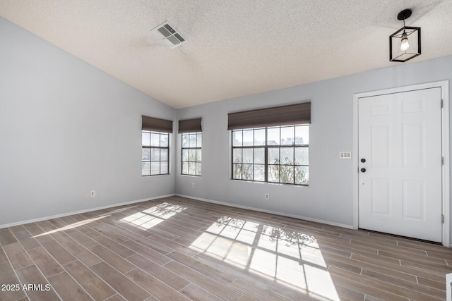 foyer with lofted ceiling, a wealth of natural light, and a textured ceiling