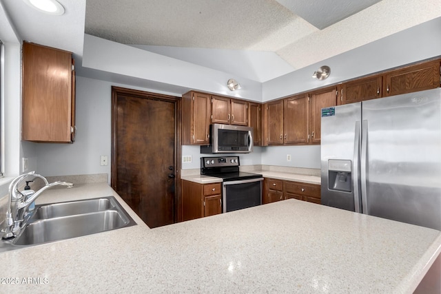 kitchen with appliances with stainless steel finishes, lofted ceiling, sink, kitchen peninsula, and a textured ceiling