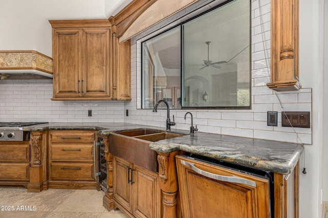 kitchen featuring ceiling fan, tasteful backsplash, stainless steel gas stovetop, sink, and dark stone counters