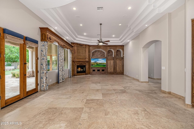 unfurnished living room with ceiling fan and a tray ceiling