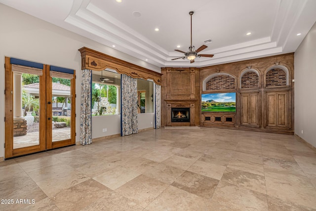 unfurnished living room with ceiling fan, a wealth of natural light, and a raised ceiling