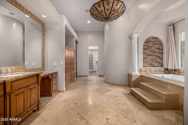 bathroom with ornate columns, vanity, and a bathing tub