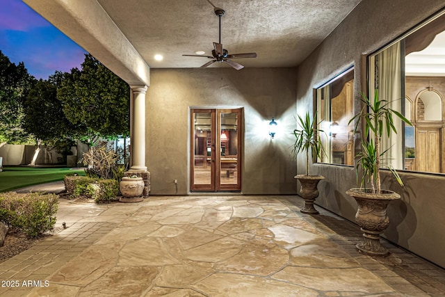 patio terrace at dusk featuring ceiling fan and french doors