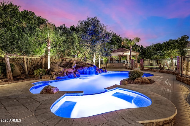 pool at dusk with a patio area, a gazebo, and an in ground hot tub