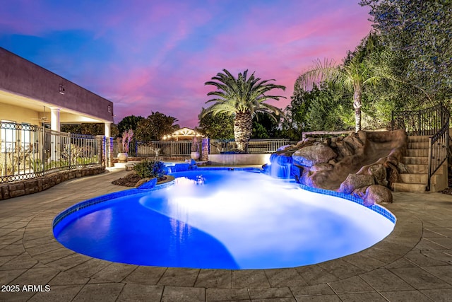 pool at dusk featuring a patio area and pool water feature