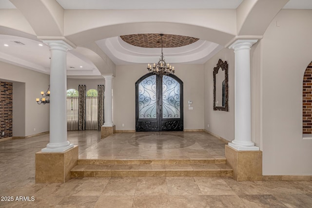 entrance foyer featuring a chandelier, a raised ceiling, and french doors