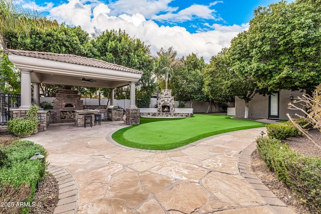 view of patio / terrace with ceiling fan, an outdoor fireplace, and an outdoor kitchen