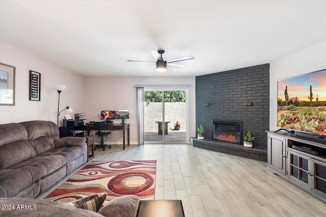 living area featuring a fireplace, ceiling fan, and light wood-type flooring