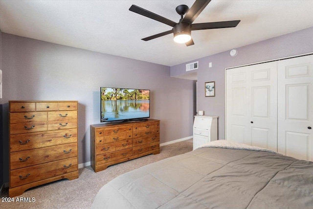 bedroom featuring a closet, ceiling fan, visible vents, baseboards, and light colored carpet