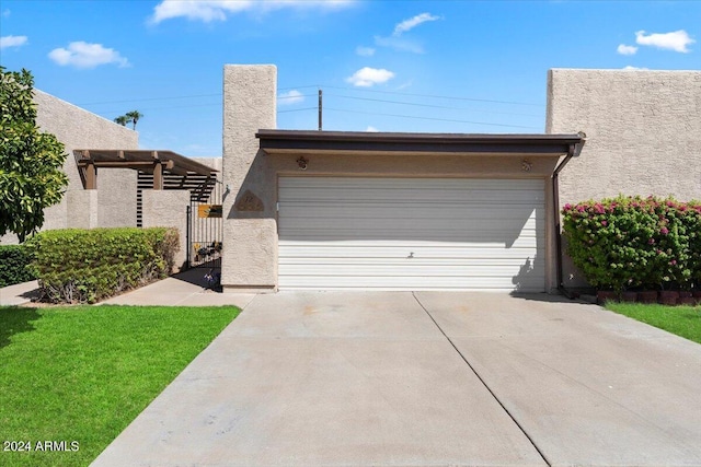 view of front of house featuring a front yard, a garage, a gate, concrete driveway, and stucco siding