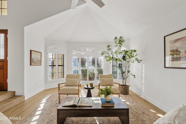 living room featuring baseboards, high vaulted ceiling, and wood finished floors