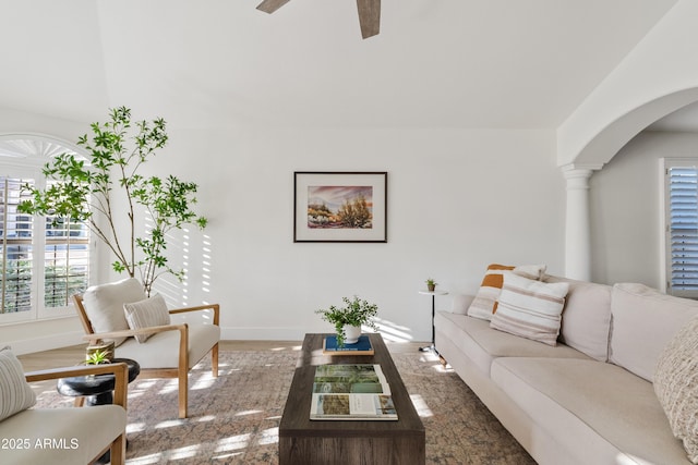 living room featuring arched walkways, baseboards, and a ceiling fan