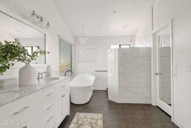 bathroom featuring a walk in shower, a sink, tile walls, double vanity, and a soaking tub