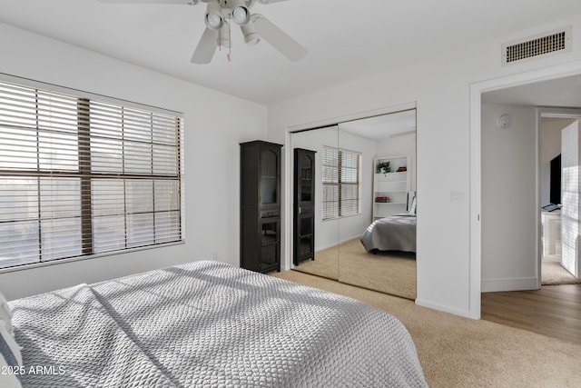 bedroom featuring baseboards, visible vents, ceiling fan, a closet, and light colored carpet