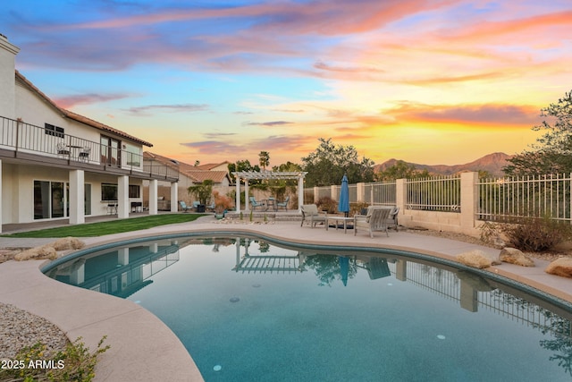 pool at dusk featuring a fenced in pool, fence, a patio area, a mountain view, and a pergola