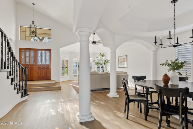 foyer entrance with decorative columns, arched walkways, stairs, and light wood finished floors