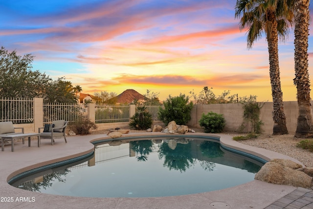 pool at dusk with a fenced in pool, a fenced backyard, and a patio area