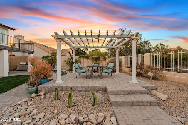 patio terrace at dusk featuring a fenced backyard and a pergola