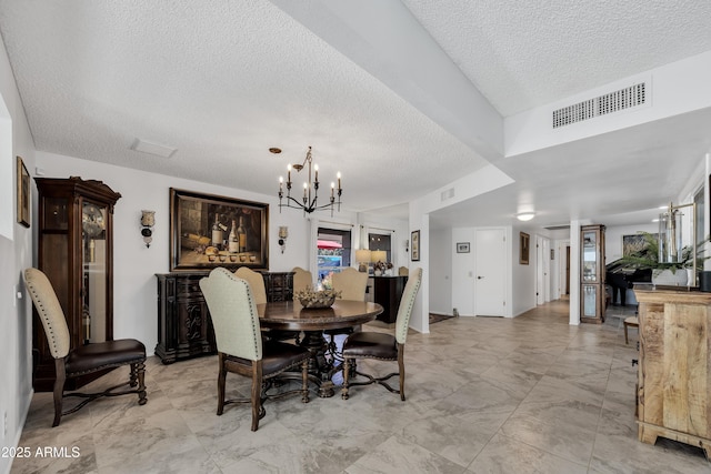 dining area with a textured ceiling and a notable chandelier