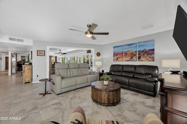 living room featuring ceiling fan and a textured ceiling