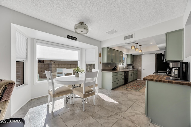 kitchen with wooden counters, green cabinets, a raised ceiling, and tasteful backsplash