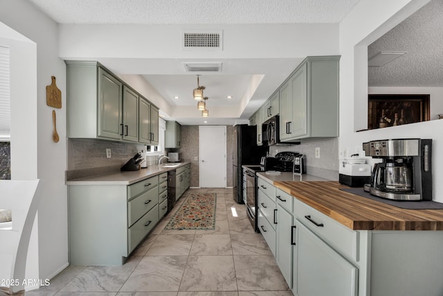 kitchen featuring black appliances, decorative backsplash, sink, a raised ceiling, and butcher block countertops