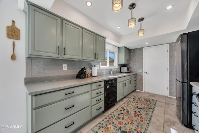 kitchen with pendant lighting, black appliances, decorative backsplash, sink, and green cabinetry