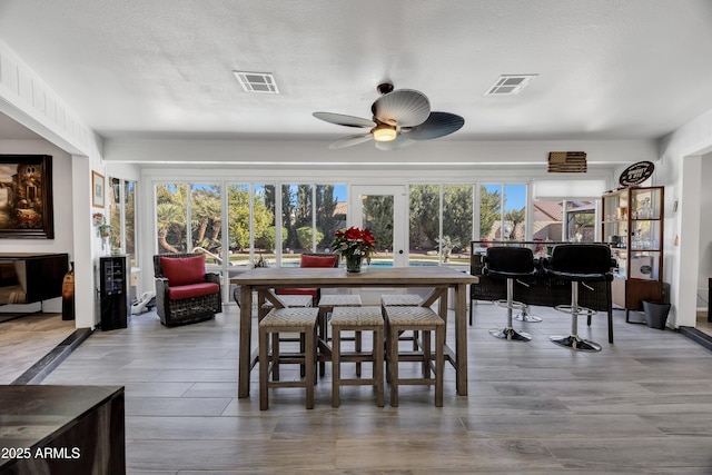 dining room featuring a textured ceiling, ceiling fan, a healthy amount of sunlight, and french doors