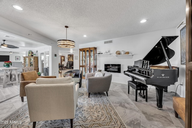 living room with ceiling fan with notable chandelier and a textured ceiling