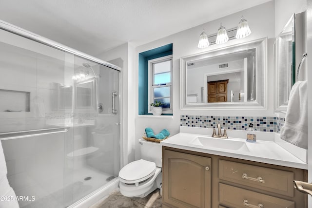 bathroom featuring vanity, toilet, decorative backsplash, and a shower with door