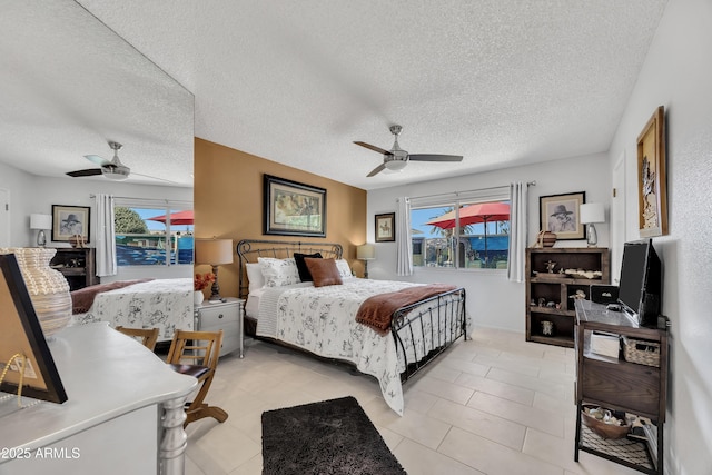 bedroom featuring ceiling fan, light tile patterned flooring, and a textured ceiling