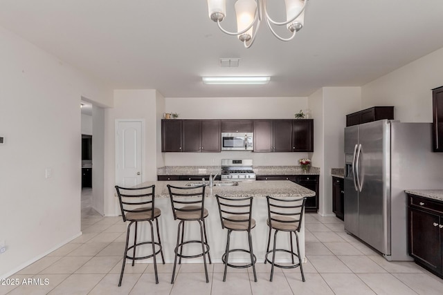 kitchen featuring appliances with stainless steel finishes, an island with sink, and dark brown cabinetry